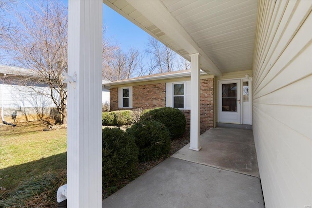 doorway to property featuring brick siding and a lawn