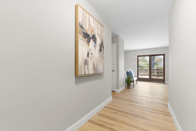 hall with light wood-type flooring, baseboards, and french doors