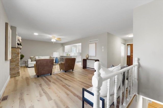 living area with visible vents, baseboards, light wood-type flooring, and a ceiling fan