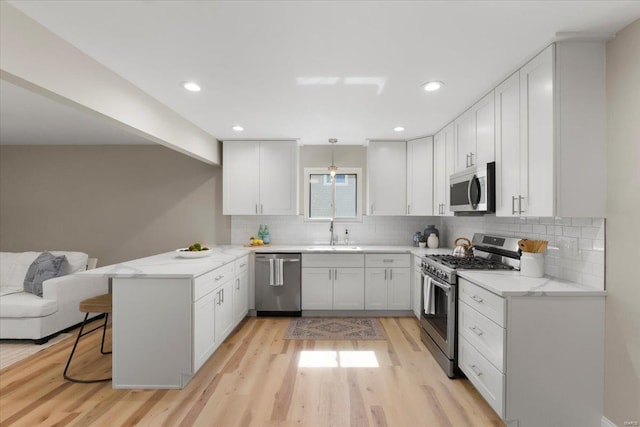 kitchen with a sink, stainless steel appliances, backsplash, and a peninsula