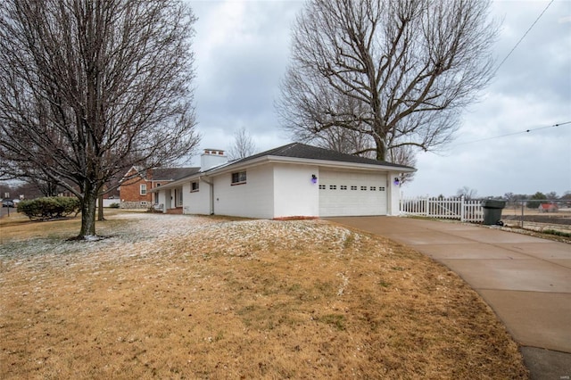 view of front of house with driveway, an attached garage, a chimney, and fence