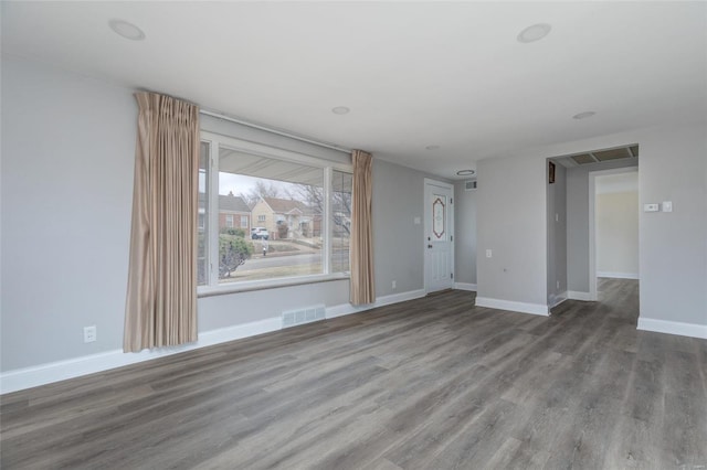 unfurnished room featuring baseboards, visible vents, and wood finished floors