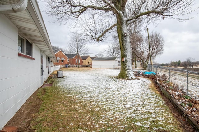 snowy yard featuring central AC and fence