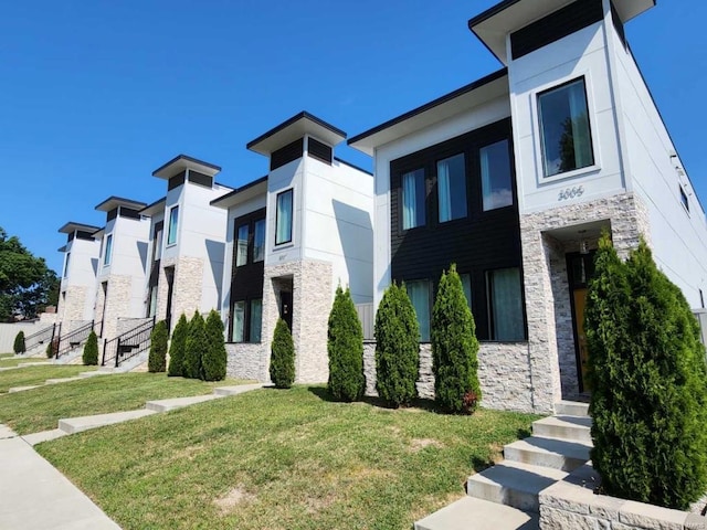 view of front of house with stone siding, a front lawn, and stucco siding