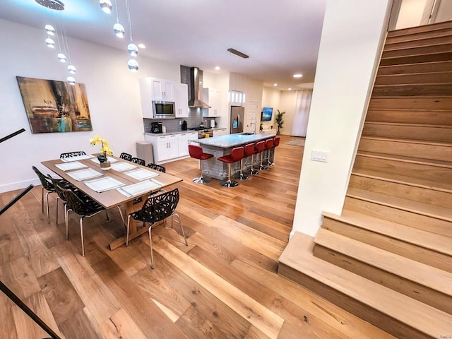 dining area with light wood finished floors, stairway, and recessed lighting