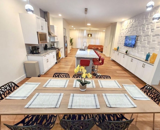 kitchen with light wood-style flooring, white cabinetry, stainless steel appliances, and a sink