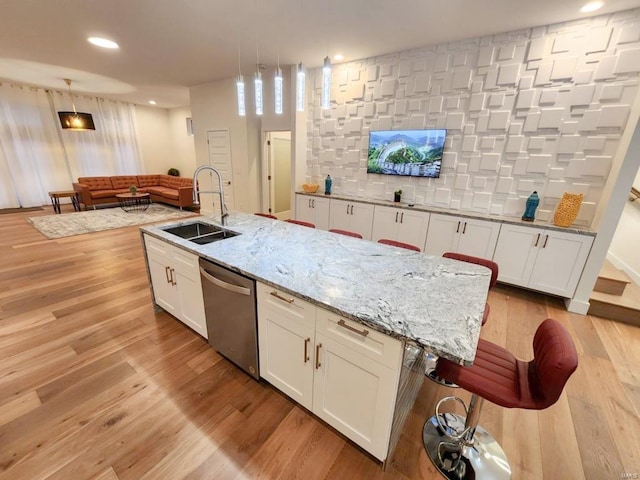 kitchen featuring a sink, light wood-style flooring, white cabinetry, and dishwasher