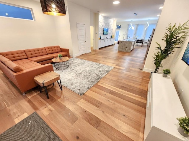 living area featuring light wood-type flooring, baseboards, and recessed lighting