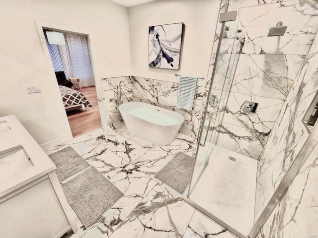 ensuite bathroom featuring marble finish floor, a marble finish shower, a freestanding bath, connected bathroom, and vanity