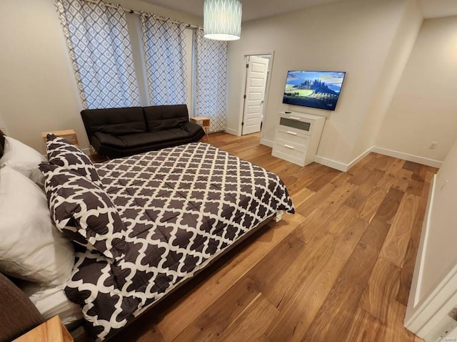 bedroom featuring light wood finished floors and baseboards