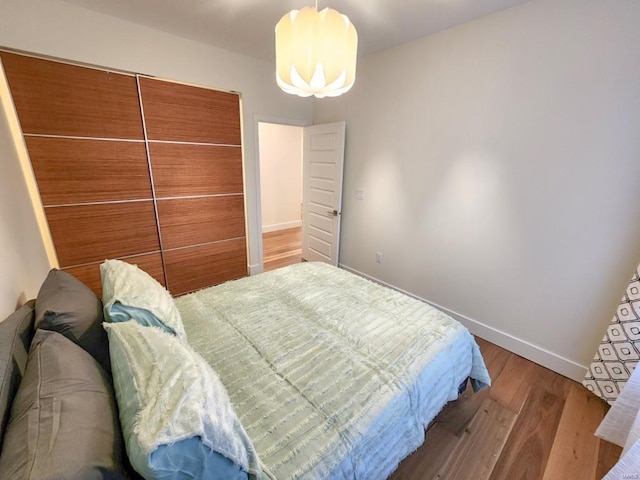 bedroom with a notable chandelier, wood finished floors, and baseboards