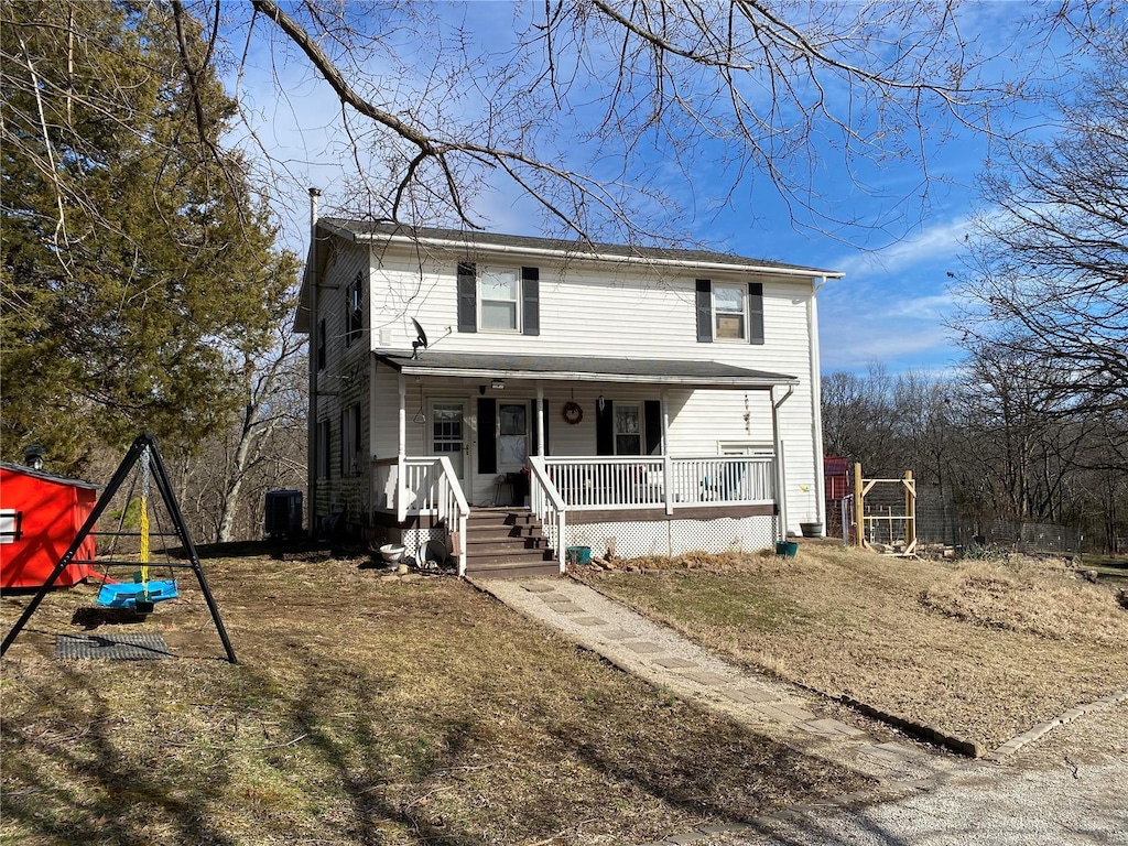 traditional-style home with covered porch, a playground, and central AC