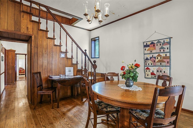 dining room featuring wood-type flooring, stairway, a chandelier, and crown molding