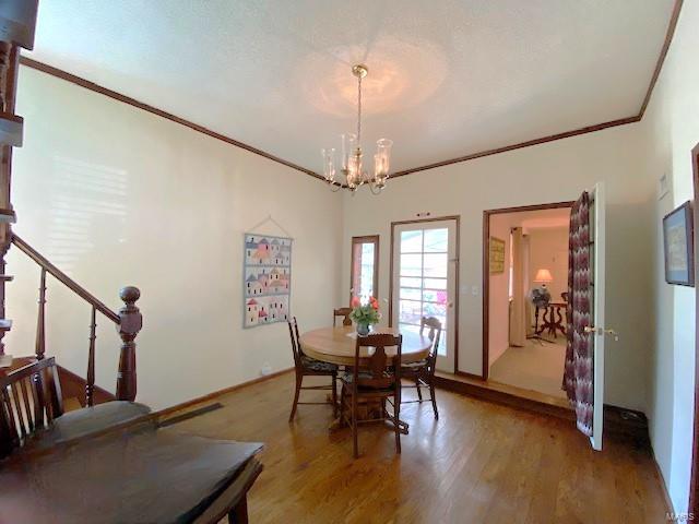 dining space featuring crown molding, an inviting chandelier, stairs, and light wood-style floors