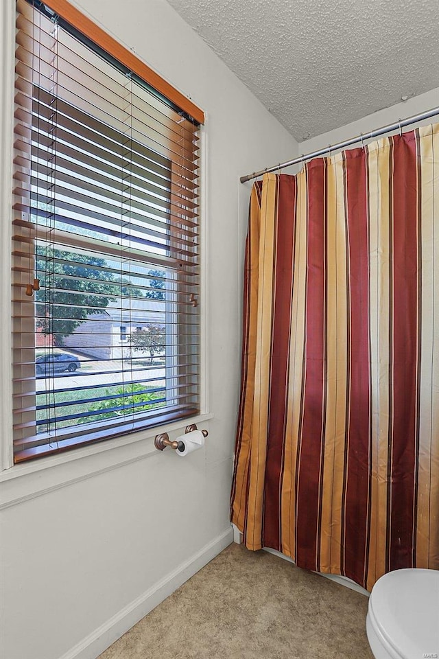 bathroom with toilet, baseboards, and a textured ceiling