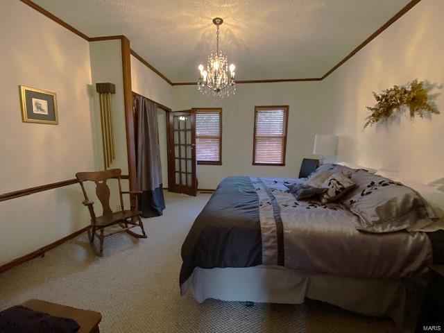 carpeted bedroom featuring a chandelier, ornamental molding, and baseboards