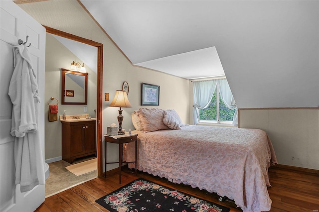 bedroom with lofted ceiling, wood-type flooring, baseboards, and ensuite bathroom