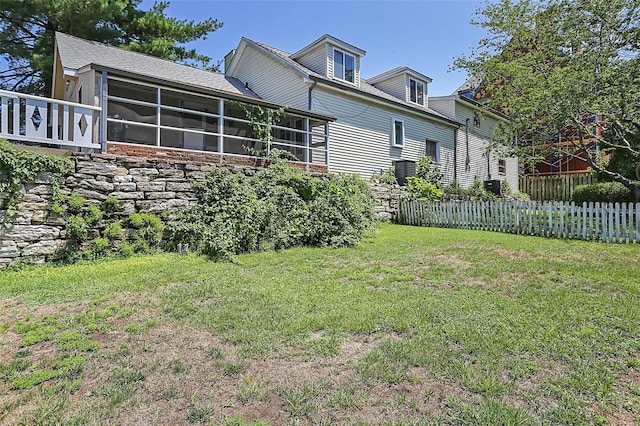 exterior space featuring a sunroom, a lawn, and fence