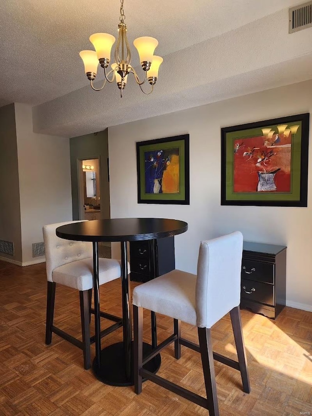 dining room featuring a textured ceiling, a chandelier, and visible vents