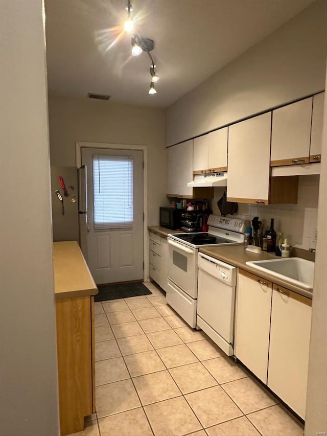 kitchen featuring under cabinet range hood, white appliances, a sink, white cabinetry, and visible vents