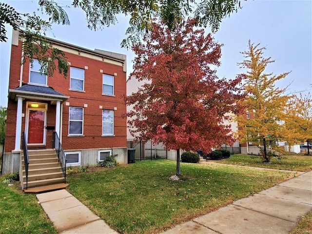 townhome / multi-family property featuring brick siding, fence, and a front yard