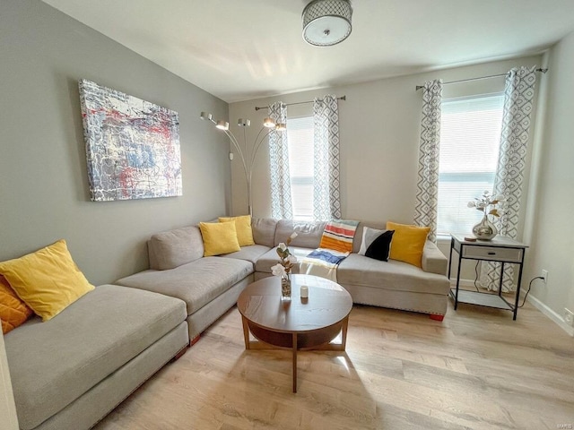 living area with light wood-type flooring, a healthy amount of sunlight, and baseboards