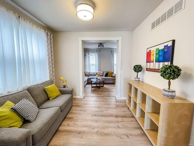 living room featuring visible vents, light wood-style flooring, and baseboards