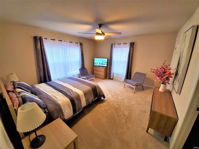 bedroom with light colored carpet, ceiling fan, and baseboards