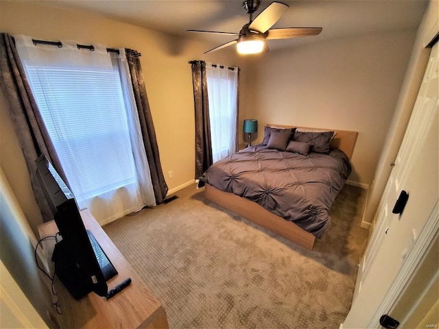 carpeted bedroom featuring multiple windows, ceiling fan, and baseboards