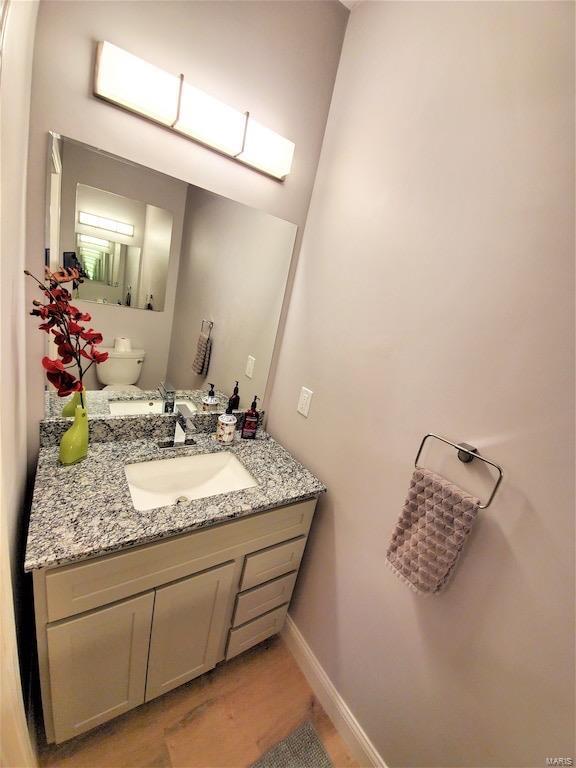 bathroom with wood finished floors, vanity, and baseboards