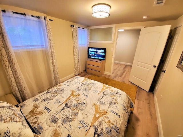 bedroom featuring wood finished floors, visible vents, and baseboards