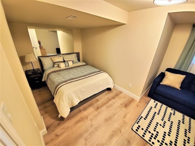 bedroom with light wood-style floors, visible vents, and baseboards