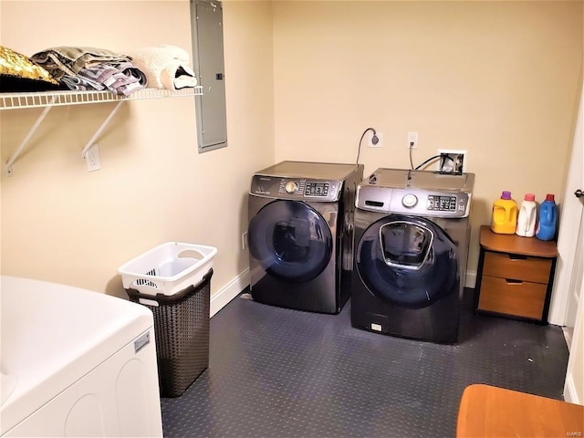 clothes washing area with laundry area, washing machine and dryer, electric panel, and baseboards