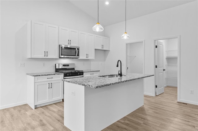 kitchen with light wood-style flooring, stainless steel appliances, a sink, white cabinetry, and light stone countertops