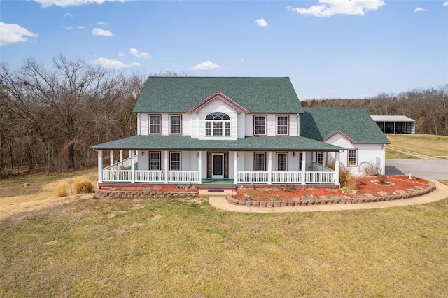 country-style home with roof with shingles, a porch, and a front lawn