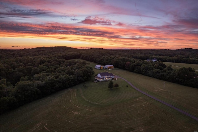 aerial view at dusk featuring a view of trees