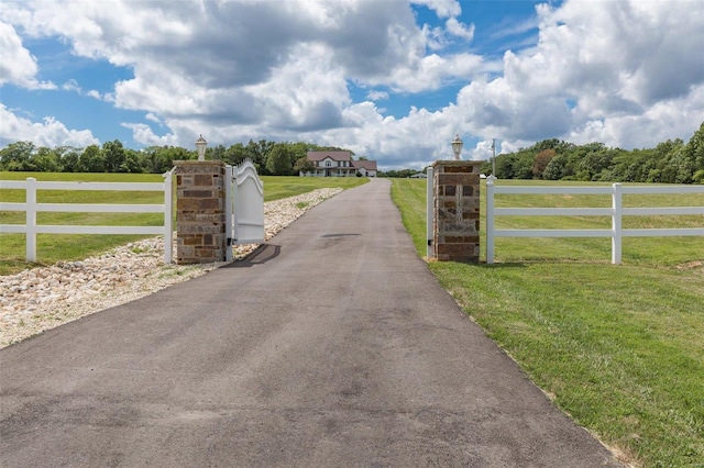 view of gate featuring a rural view, a yard, and fence