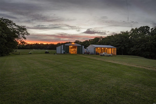 yard at dusk with a detached garage and an outbuilding