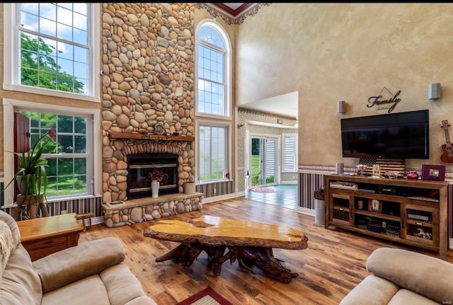 living area featuring wood finished floors, a fireplace, baseboards, and a towering ceiling