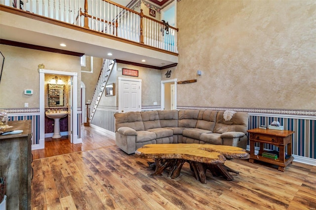 living area featuring hardwood / wood-style floors, crown molding, a high ceiling, and stairway