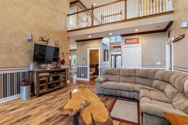 living area with crown molding, recessed lighting, wainscoting, a high ceiling, and wood finished floors