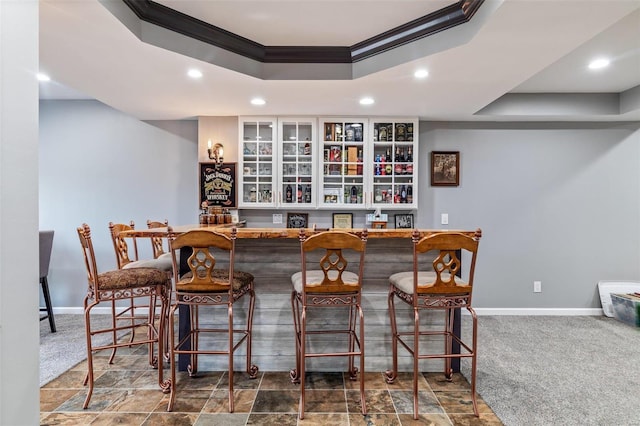bar featuring a raised ceiling, baseboards, and carpet floors