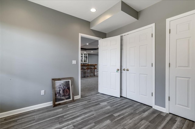 unfurnished bedroom with recessed lighting, a closet, baseboards, and wood finished floors