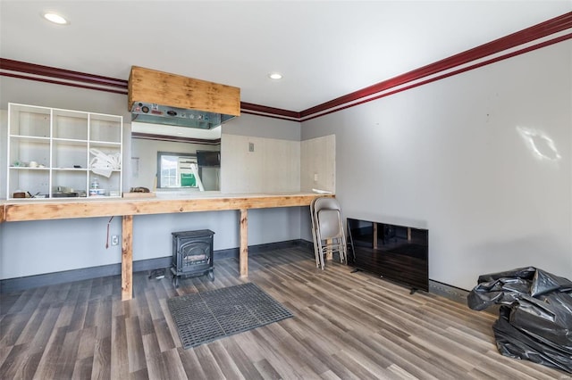 interior space featuring a wood stove, wood finished floors, baseboards, and ornamental molding