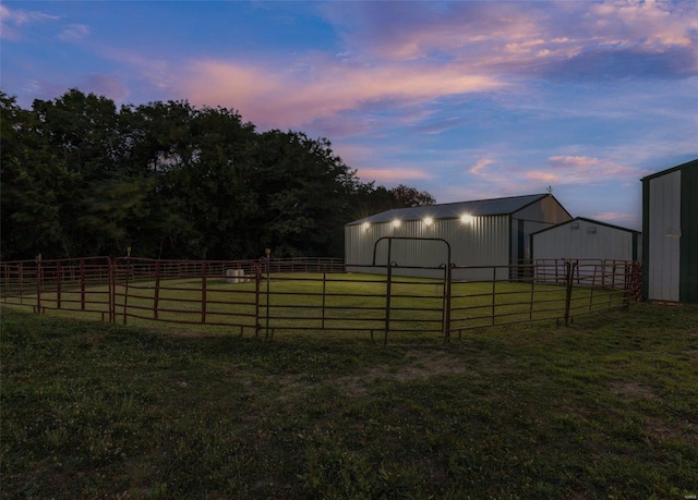 yard at dusk with a pole building, an exterior structure, an outdoor structure, and fence