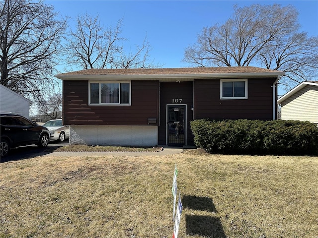 raised ranch with a front lawn and brick siding