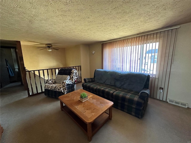 carpeted living room with a textured ceiling, ceiling fan, and visible vents