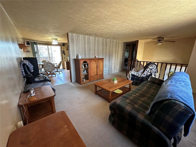 living area with a ceiling fan, carpet, and a textured ceiling