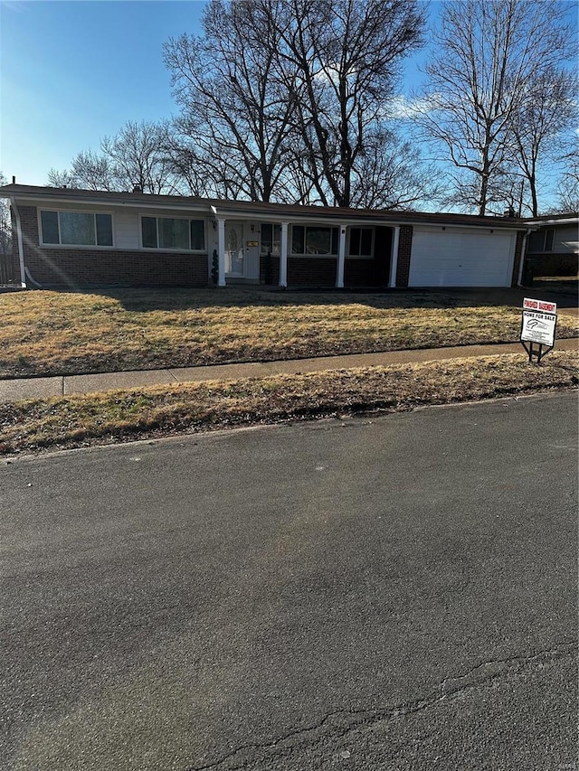 view of front of property with brick siding, an attached garage, and a front lawn