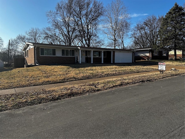 single story home featuring a garage, brick siding, and driveway